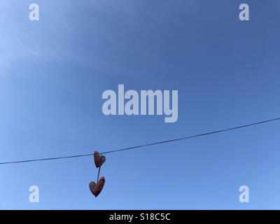 Ballons en forme de coeur accrocher sur un fil au-dessus d'une rue. Banque D'Images