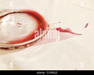 Verre vide de vin rouge et de tache de vin sur la nappe. Banque D'Images