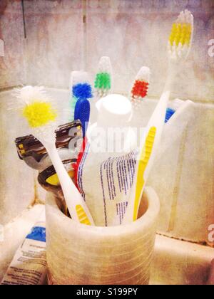 Un min dans une salle de bains contenant des brosses à dents et dentifrice. Banque D'Images