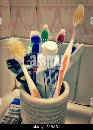 Brosses à dents et du dentifrice dans un bécher dans la salle de bains. Banque D'Images
