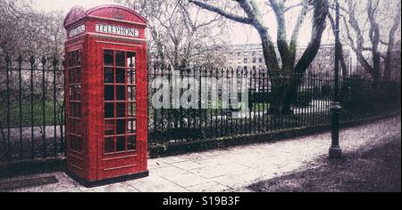 Un rouge lumineux London Téléphone fort sur une rue de Londres. Banque D'Images