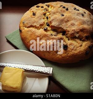 Irish soda bread au sommet d'une serviette verte avec une pointe de beurre dans le plat avec un couteau Banque D'Images