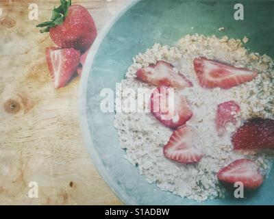 Bon matin porridge au petit-déjeuner rouge mûre fraises d'avoine et le lait d'amande dans un bol vert aqua sur bois vintage retro filtre et copiez l'espace. Mode de vie sain et délicieux aliments. Banque D'Images