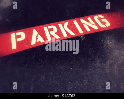 Mot 'parking' inscrit sur la bande rouge sur la chaussée. Copyspace. Banque D'Images