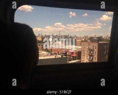 Une femme regarde l'horizon de Manhattan à partir de la fenêtre d'un train Amtrak qui traverse l'Astoria, Queens, New York Banque D'Images