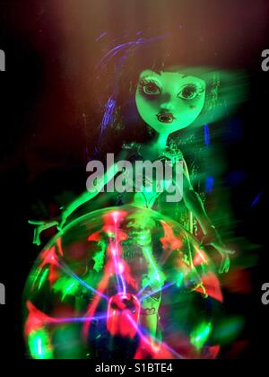 Un jouet Monster High poupée avec maquillage gothique se tient derrière un plasma rougeoyant orb, avec effet fantomatique. Banque D'Images