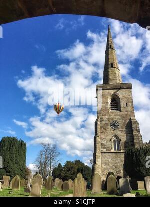 Hot Air ballon flottant près d'une église du village Banque D'Images