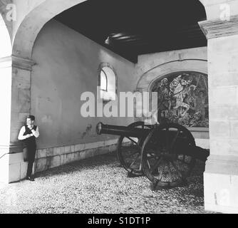 Un homme fume une cigarette dans la partie ancienne de Genève en face d'un vintage Cannon. Banque D'Images