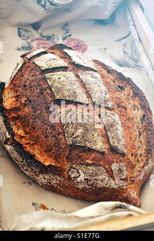 Une miche de pain au levain avec une croûte croustillante affiche dans un panier à pain rustique. Boulangerie artisanale. Banque D'Images