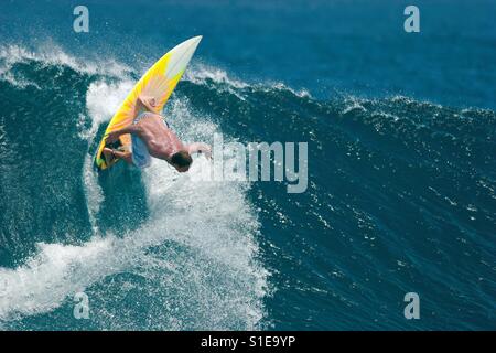 Un surfeur mâle exécute une mesure radicale sur un beau bleu océan vagues. Banque D'Images
