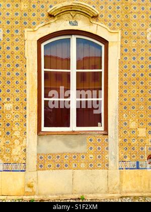 Fenêtre contre le carrelage à motifs sur un mur de chambre à Faro, Portugal Banque D'Images