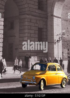 Fiat 500 jaune éclaboussé de couleurs dans une scène en noir et blanc avec des arcades Banque D'Images