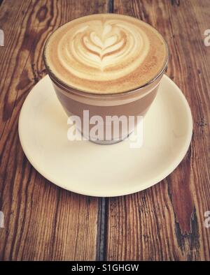 Télévision café blanc dans une tasse en verre dans une table en bois Banque D'Images