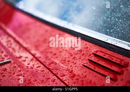 Gouttes de pluie sur la peinture ciré d'une voiture rouge Banque D'Images