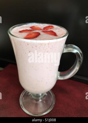 Un cocktail de fraises garnie de myrtilles est dans un verre sur la table. Banque D'Images