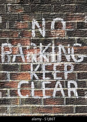 Un signe peint à la main sur un mur de brique en disant 'NO PARKING GARDER CLEAR'. Banque D'Images