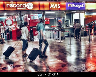 Les voyageurs ayant passé la marche sacs wheelie location de voitures salon en El Altet aéroport, Alicante, Espagne Banque D'Images
