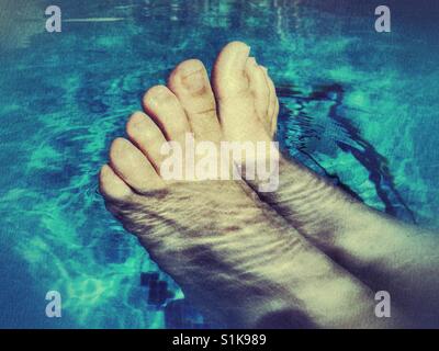 Relations sérieuses in de l'été. Pieds de femme dans la piscine, rester au frais Banque D'Images