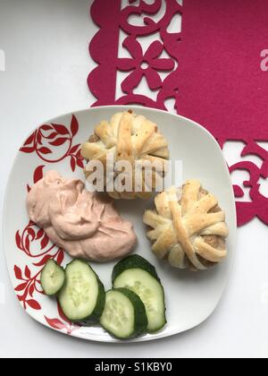 Boulettes de viande hachée cuite au four enveloppé dans des bandes de pâte feuilletée. Des grappes de viandes hachées et de la pâte. Ils se couchaient dans une assiette. Ensuite, ​​Cucumbers en tranches et la sauce. Banque D'Images