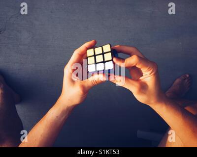 Point de vue tourné d'un Rubik's Cube l'être un jeune homme. Banque D'Images