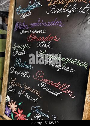 Tableau situé à l'extérieur du menu d'un bar à tapas avec des éléments à offrir rédigé en anglais et en espagnol Banque D'Images