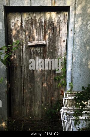 Weathered Wood porte à temps vieux hangar avec pile de windows inutilisés à côté Banque D'Images