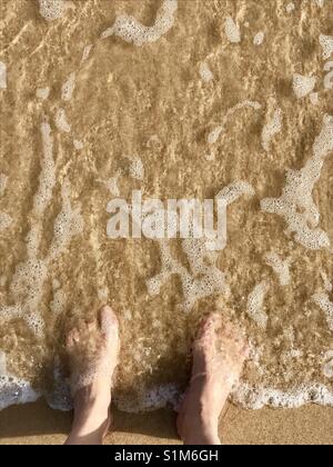 Pieds de femme au bord de la mer. Banque D'Images