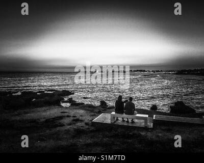 Image en noir et blanc d'un couple à la recherche aux feux de Paphos dans la distance Banque D'Images