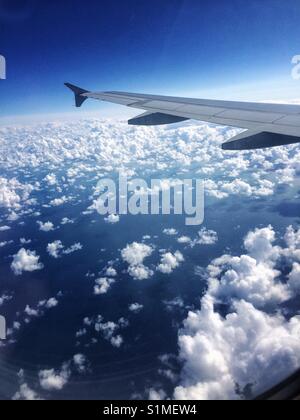 Vue depuis la fenêtre d'un avion, les nuages, l'aile montrant et ciel bleu. Banque D'Images