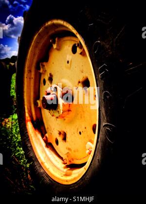 Gros plan du pneu arrière du tracteur et de la roue dans le champ vert avec ciel bleu Banque D'Images