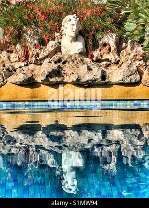 Buste romain et partie intégrante de rocaille reflète dans une piscine carrelée bleu Banque D'Images