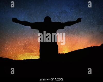 Silhouette d'un homme avec des bras tendus au coucher du soleil Banque D'Images