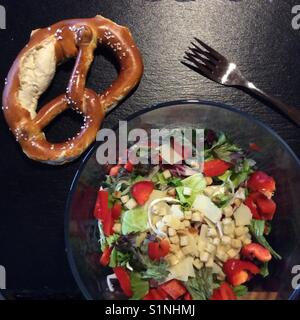 Grana padano, salade bavaroise originale bretzel et fourchette sur fond noir de la table de cuisine Banque D'Images