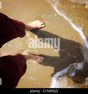 Les pieds de la personne sur le sable de la plage Banque D'Images