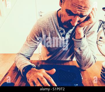 Triste et ennuyé scandinave d'âge moyen man working on laptop at home Banque D'Images