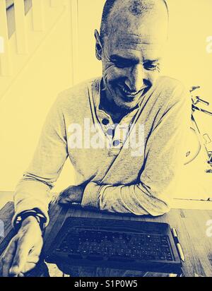 Smiling middle aged man working on laptop scandinave à la maison Banque D'Images