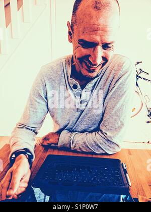 Smiling middle aged man working on laptop scandinave à la maison Banque D'Images
