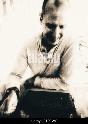 Happy smiling middle aged man working on laptop scandinave à la maison Banque D'Images