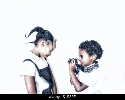 Frères et sœurs jouant avec un appareil photo vintage. Banque D'Images