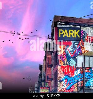 Une photo artistique abstraite de graffitis élaborés sur le flanc d'un bâtiment à New York, contre un ciel bleu et rose pastel dramatique Banque D'Images
