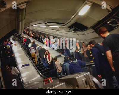 Les gens voyagent sur les escaliers mécaniques à la station de métro Victoria à Londres, Angleterre Banque D'Images