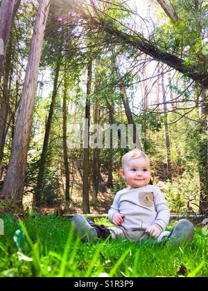 Bébé assis dans la forêt Banque D'Images