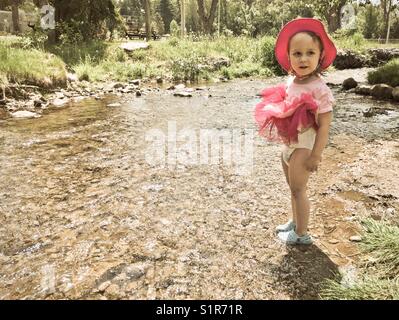 Photo de nostalgique Girl standing in stream en relevant sa robe montrant sa couche Banque D'Images