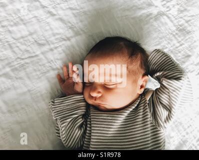 Un bébé nouveau-né fille endormie dans une chemise rayée. Banque D'Images