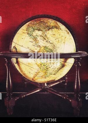 Globe antique du monde dans le support en bois avec fond rouge foncé montrant l'Amérique du Nord et du Sud Banque D'Images