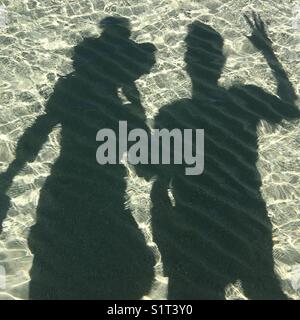 Ombre d'un couple dans l'eau peu profonde à la plage Banque D'Images