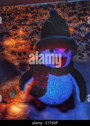 La lumière de Noël jusqu'à l'ornement de pingouin avec un fil star fairy light. Banque D'Images