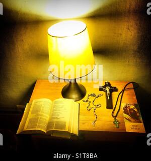 Une bible, un chapelet, une croix, un crucifix et une prière illuminée par une lampe dans un hôtel à Guanajuato au Mexique. Banque D'Images