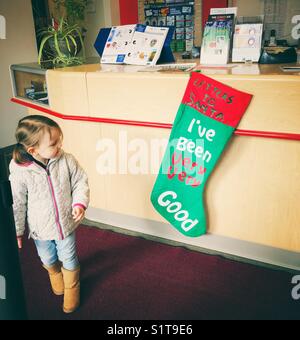 Jeune fille à la recherche de lettres au Père Noël stocking accrochées dans les bureaux de Postes Canada pour les enfants d'envoyer leurs lettres au Père Noël Banque D'Images