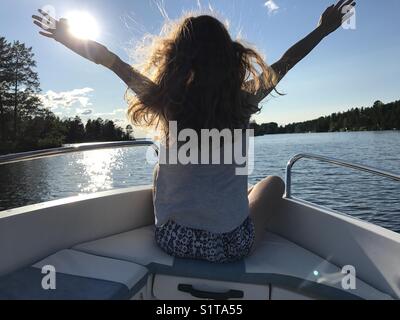 Fille avec un bras cassé dans le plâtre bénéficiant en bateau sur un lac en été Banque D'Images